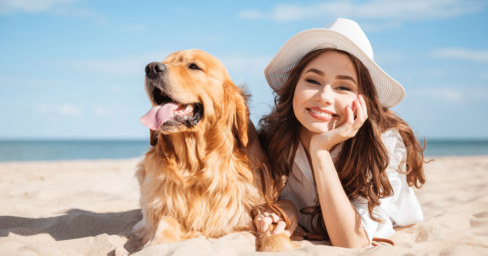 happy dog on beach with woman in sun hat