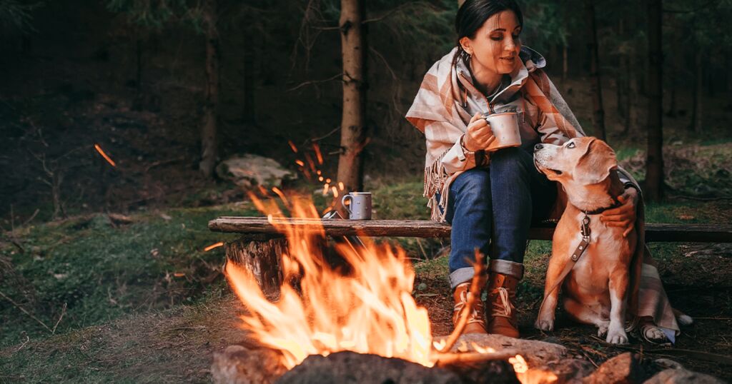 Hund mit Frau am Campingfeuer