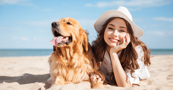 Une jeune femme et son chien allongés sur la plage côte-côte. 