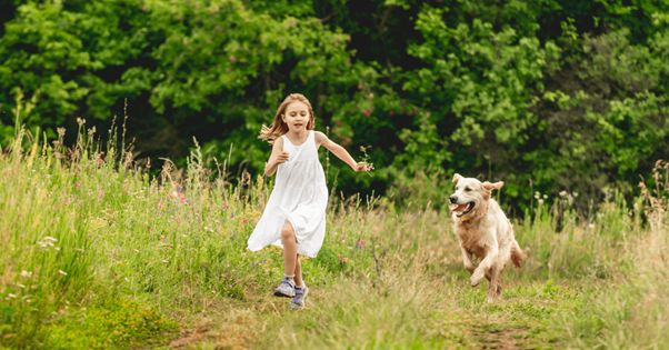 Une jeune fille courant avec son chien dans un champs.